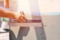 Hands of an old manual worker with wall plastering tools renovating house