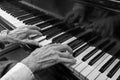 Hands of an old musician playing music on the keyboard of a grand piano, black and white image, concept for culture, art and Royalty Free Stock Photo