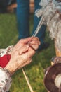 Hands of the old woman spinning thread from a bundle of sheep wool on a Sunny day. Royalty Free Stock Photo