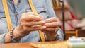 hands of an old woman threading a sewing needle