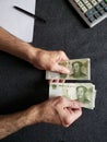 hands of an older man counting chinese banknotes