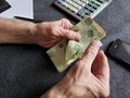 hands of an older man counting Mexican banknotes