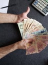hands of an older man holding argentinean banknotes