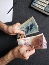 hands of an older man holding argentinean banknotes