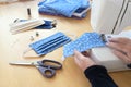 Hands of an older woman on a sewing machine making community face masks during the coronavirus pandemic, homemade protection