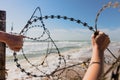 Hands open barbed wire outdoors at beach. Royalty Free Stock Photo