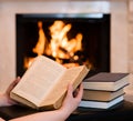 Hands with open book near the fireplace