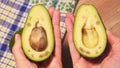 Hands open cut green avocado, first-person view