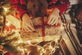 hands opening Christmas gift box on at golden beautiful christmas tree with lights in festive room. winter holiday atmospheric mo Royalty Free Stock Photo