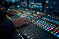Hands operating a brightly lit, complex audio mixing console in a dark control room Royalty Free Stock Photo