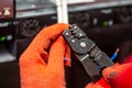 Hands in orange insulating gloves work with crimping pliers and cables. Horizontal orientation Royalty Free Stock Photo