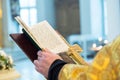 The hands of an Orthodox priest, a cross and a prayer book.