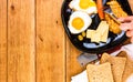 Hands over breakfast plate. Fried egg, wholegrain toast, cheese, hotdog and cup of coffee for breakfast over wooden table, top Royalty Free Stock Photo