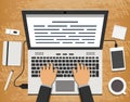 Hands over laptop on wooden desk with office objects around