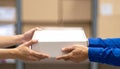 Hands Passing a White Cardboard Box in a Blurred Warehouse or Storage Area image photo Royalty Free Stock Photo