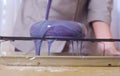 Hands of the pastry chef pouring multicolor mirror glaze on a big cake