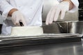 Hands pastry chef prepares a cake, cover pouring white icing, working on a stainless steel kitchen work top