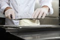 Hands pastry chef prepares a cake, cover pouring white icing, working on a stainless steel kitchen work top