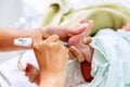 Hands of pediatric nurse holding and using Accu-Chek Fastclix needle pen for blood and glucose check stab on sick newborn baby