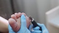 Hands of pedicurist remove old skin on client`s foot makes hardware pedicure.