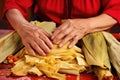 hands peeling corn husks from hot, steamed tamales