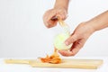Hands peeling raw onion with a knife on a cutting board Royalty Free Stock Photo