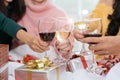 Hands of people celebrating New year party in home with wine drinking glasses and present background. New year and Christmas party Royalty Free Stock Photo
