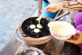 The hands of people are dropping the flour in the charcoal stove, making food snacks. Asia Street food