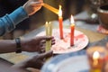 Hands of a person with a bunch of thin candles