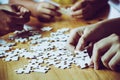 Hands of a person little child and parent playing jigsaw puzzle piece game together on wooden table at home, concept for leisure