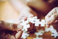Hands of a person little child and parent playing jigsaw puzzle piece game together on wooden table at home, concept for leisure Royalty Free Stock Photo
