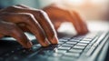 Hands of a person typing on a keyboard with natural light highlighting the focused activity of working on a desktop computer in an Royalty Free Stock Photo