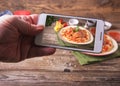 Hands with the phone takes pictures of Italian cuisine spaghetti with meatballs noodles pasta meal in a plate on a rustic wooden Royalty Free Stock Photo