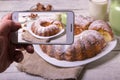 Hands with the phone takes pictures of a pie.Traditional homemade sweet round fruit cake on the plate on the rustic wooden