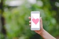 Hands and phones Pink heart screen Green nature Technology Concepts And to do business online.