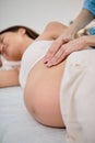 Hands of physiotherapist and osteopath giving professional massage to pregnant woman