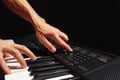 Hands of pianist play the keys of the electronic synthesizer on black background