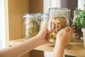 Hands picking macaroni in glass jar for preparing food