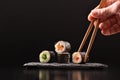 Hands picking vegetable maki sushi with chopsticks and black background Royalty Free Stock Photo