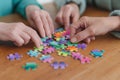 hands piecing together a vibrant jigsaw puzzle on a wooden table in a calm, cooperative setting with colorful fragments concept of