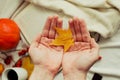 Hands with pine yellow mapleleaf on the background of an autumn still life of a cup of tea pumpkins apples and yellow leaves.