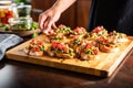 hands placing finished bruschetta on serving tray