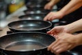 hands placing nonstick frying pans in row