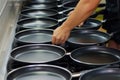 hands placing nonstick frying pans in row