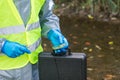 In the hands of plant samples from the river and its surroundings by a man in a special suit, side view