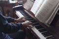 Hands playing piano while reading music sheets