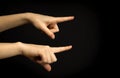 Hands point to something. Woman hand gesture, pointing sign, gesture look at this, pay attention. Black background photo