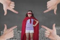 Hands pointing at girl in a super heroine custom against grey background with city illustration Royalty Free Stock Photo