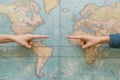 Hands pointing in opposite directions over a world map represent disagreement and division between perspectives and Royalty Free Stock Photo
