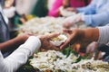 The hands of the poor handed a plate to receive food from volunteers to alleviate hunger, the concept of helping the homeless Royalty Free Stock Photo
